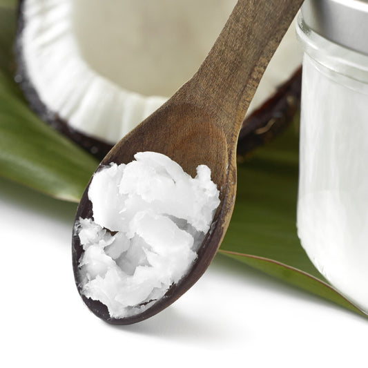 Coconut oil in a wooden spoon with a coconut and jar in the background