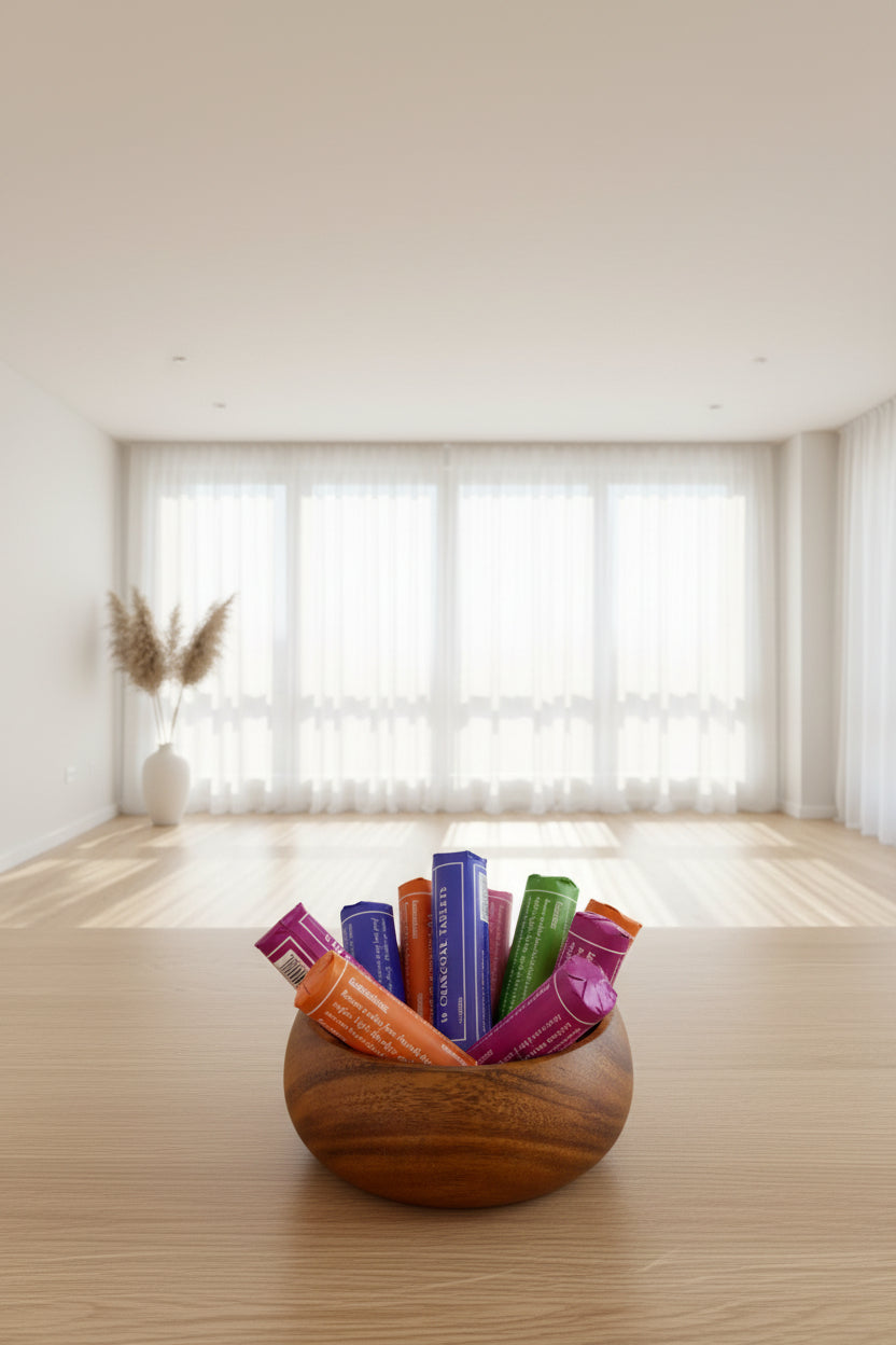Wooden bowl with purple packages labeled '10 Charcoal Tablets' on a wooden surface.
